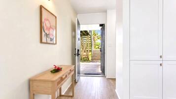 Un couloir avec un bureau en bois, un tableau encadré et une armoire blanche.