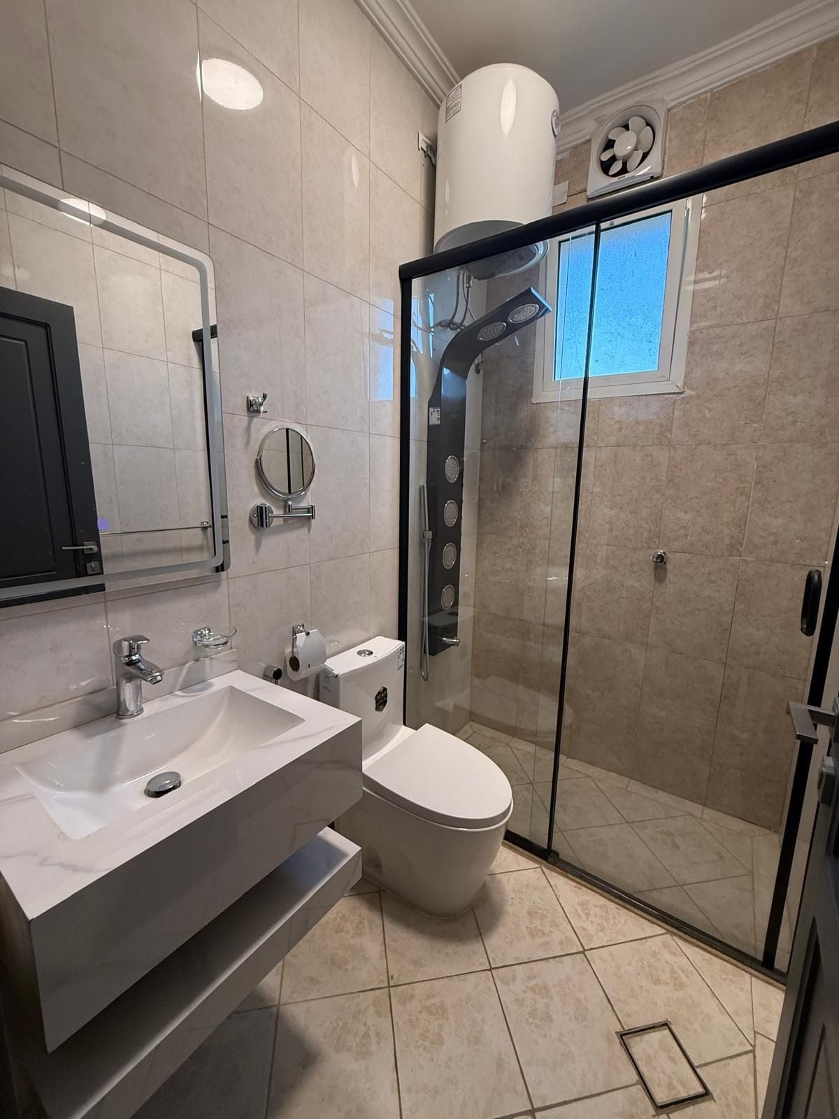 Un baño moderno con ducha envuelta en vidrio, un lavabo blanco y un inodoro.
