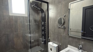 Ein modernes Badezimmer mit einer Duschkabine, einer Toilette und einem Waschbecken mit Spiegel darüber.