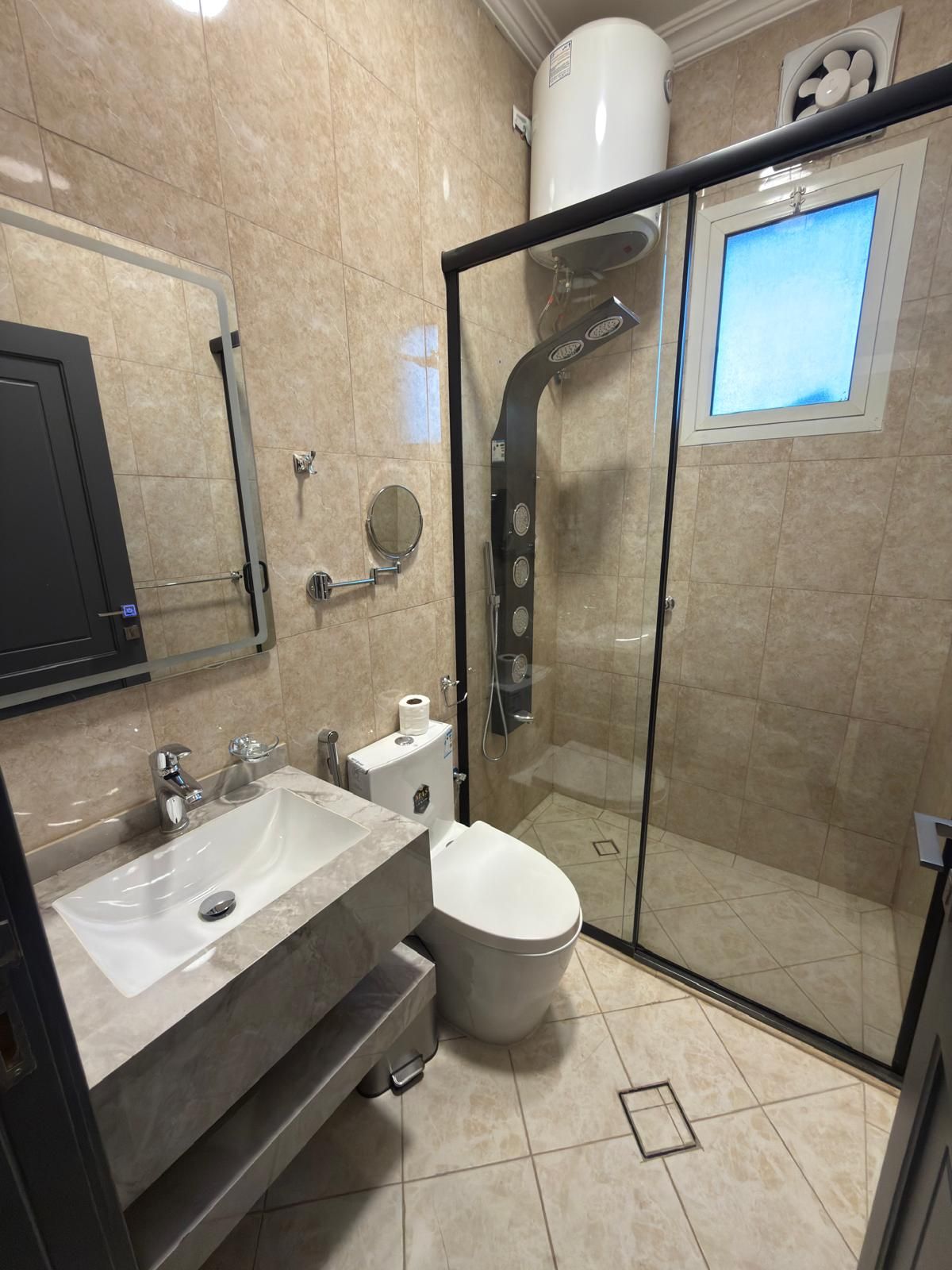A bathroom with a glass-enclosed shower, a sink, a toilet, and a mirror.