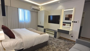 Ein Hotelzimmer mit einem Bett, einem Schreibtisch, einem Sessel, einem Fernseher und einem Spiegel.