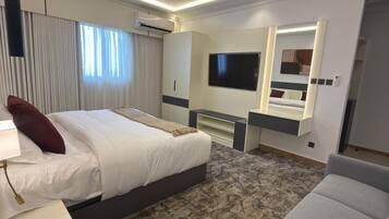 A hotel room with a bed, a desk, a chair, a TV, and a mirror.