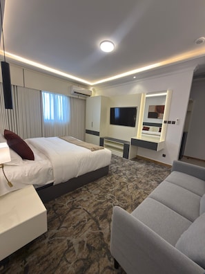 A hotel room with a bed, a desk, a chair, a TV, and a mirror. - Aurion Quba (Madinah)