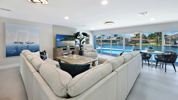 Un salon moderne avec un grand canapé, une table basse et une vue sur une piscine.