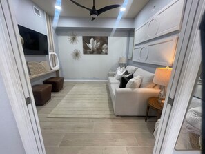 A modern living room with a sofa, a coffee table, and decorative wall art. - Cozy 2-bedroom condo in perfect Naples with cool AC (Naples)