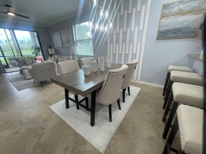 Un coin repas comprenant une table rectangulaire, quatre chaises et un tapis blanc.
