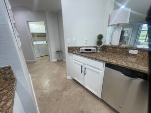 A kitchen with white cabinets, granite countertops, and stainless steel appliances. - Cozy 2-bedroom condo in perfect Naples with cool AC (Naples)