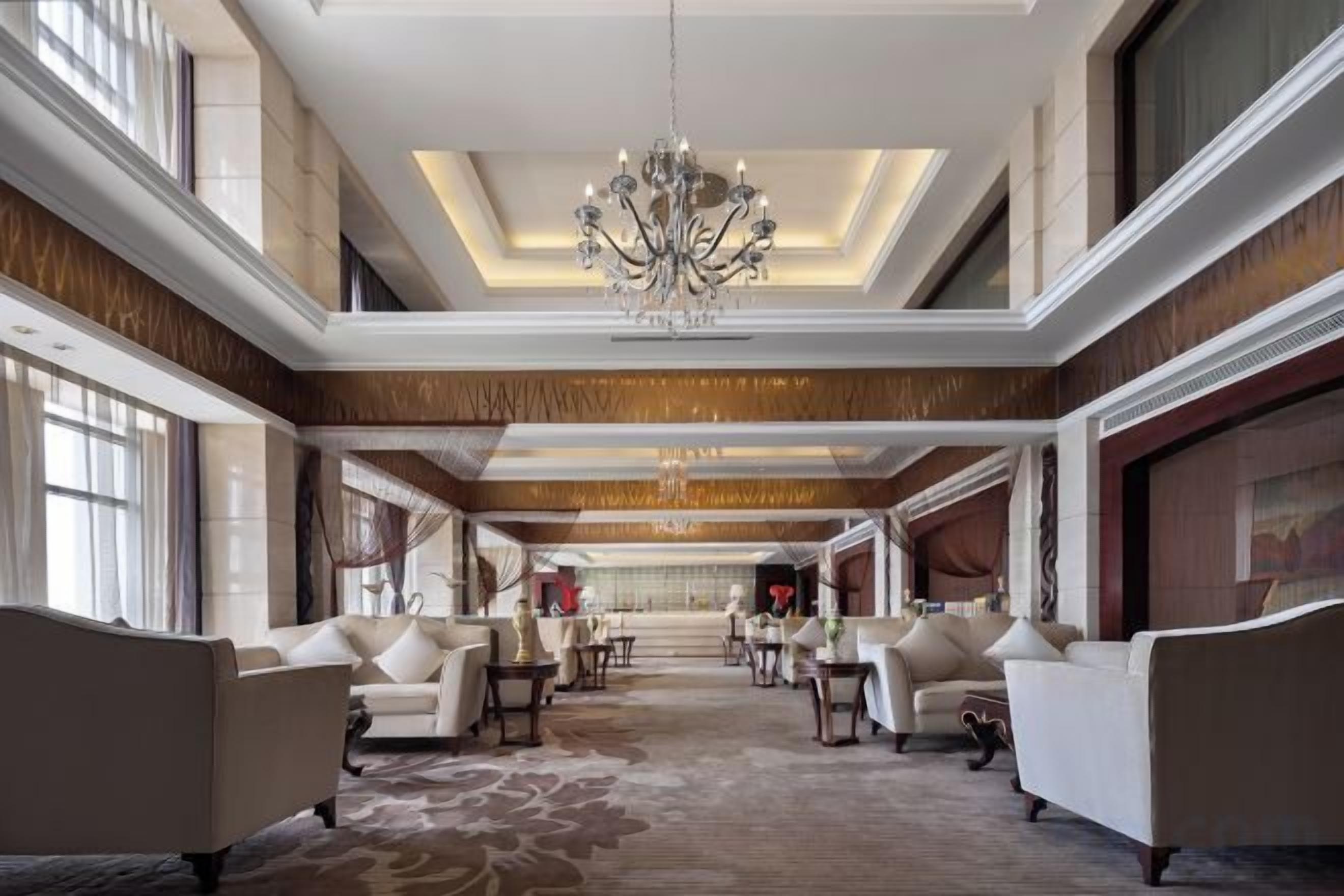 A spacious lobby with a chandelier, sofas, and a patterned carpet.