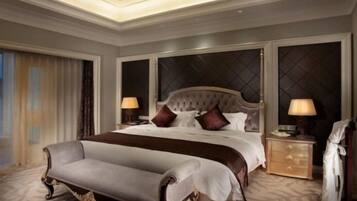 A spacious hotel room with a large bed, a sitting area, and a nightstand with lamps.