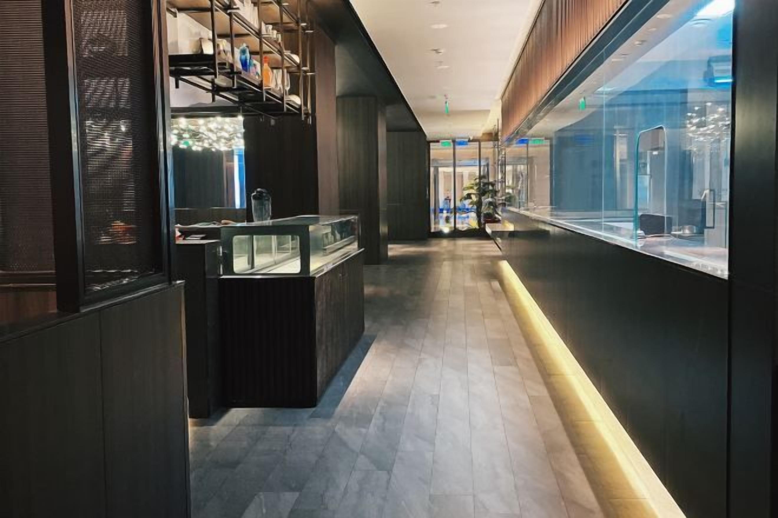 A corridor with a reception desk, glass display cases, and a modern interior design.