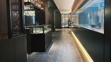 A corridor with a reception desk, glass display cases, and a modern interior design.
