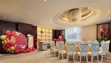 A dining area with round tables, chairs, and a decorative balloon arch.
