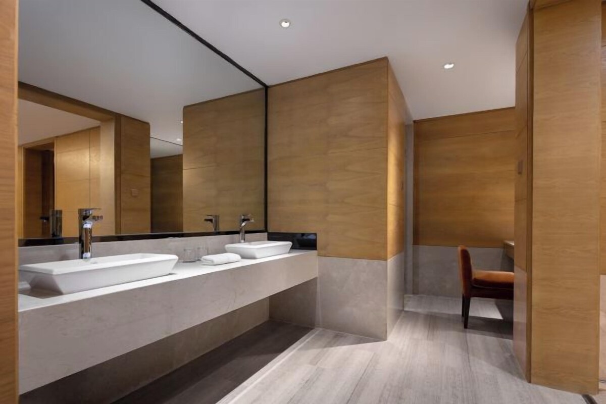 A modern bathroom with a large mirror, two sinks, and a wooden accent wall.