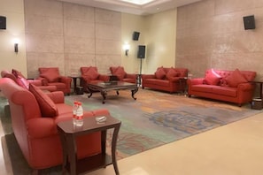 A hotel lobby with red sofas, a coffee table, and a carpeted floor.