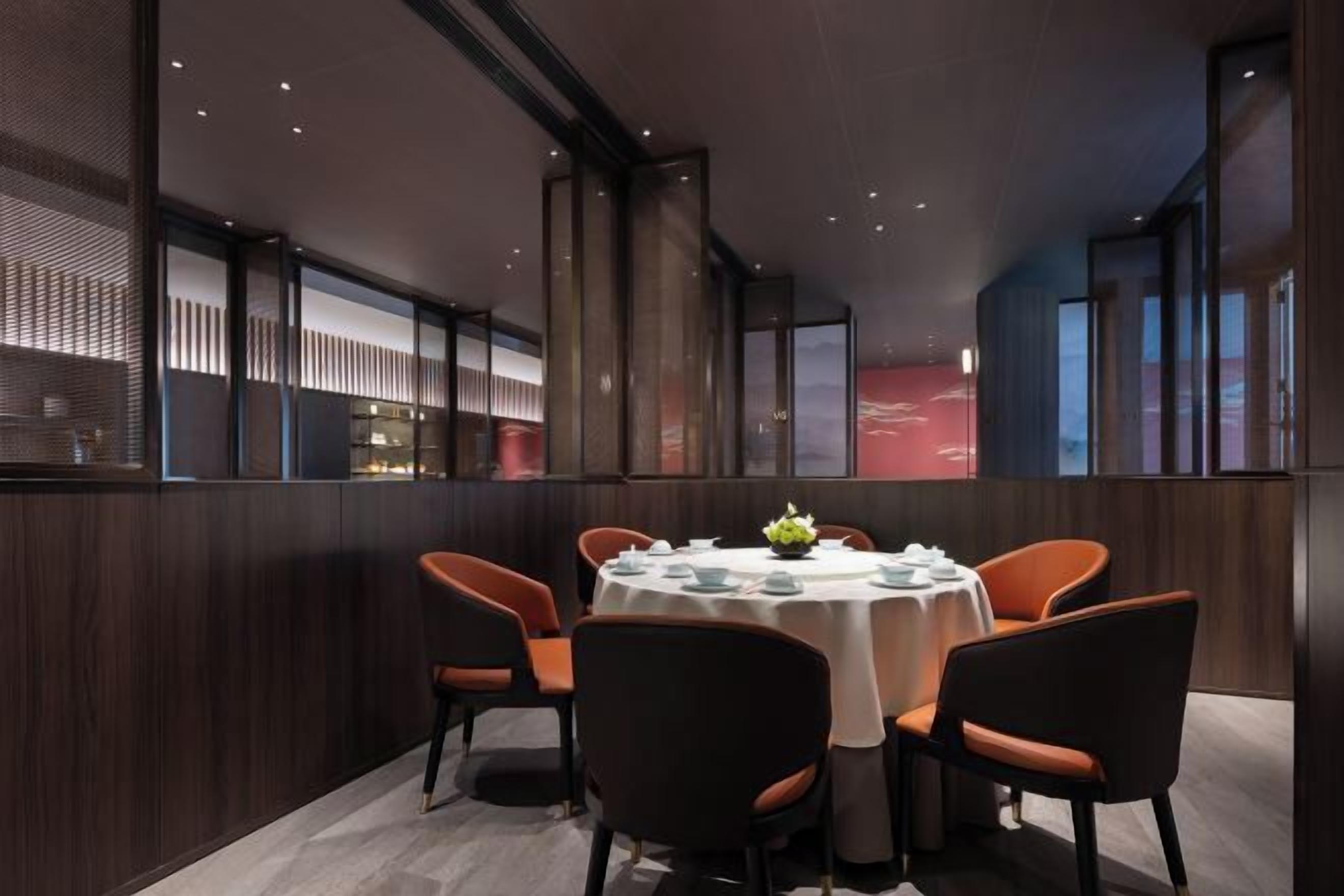 A modern dining area with a round table, four chairs, and a decorative centerpiece.