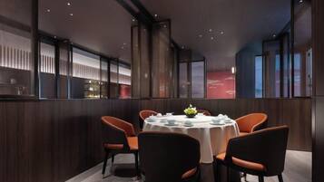 A modern dining area with a round table, four chairs, and a decorative centerpiece.