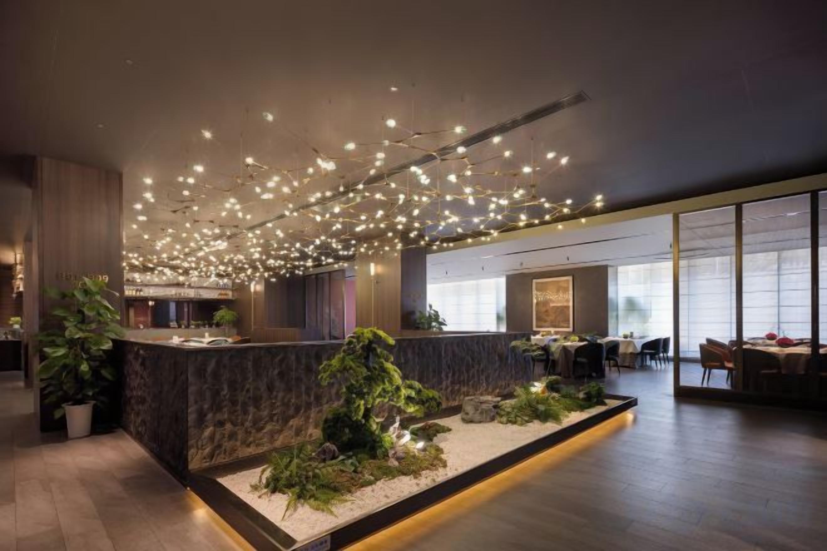 A modern hotel lobby with a reception desk, seating area, and a large window.