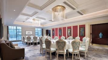 A formal dining room with a long table, chairs, and a chandelier.