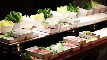Una mesa de buffet con diversos alimentos y verduras frescas.