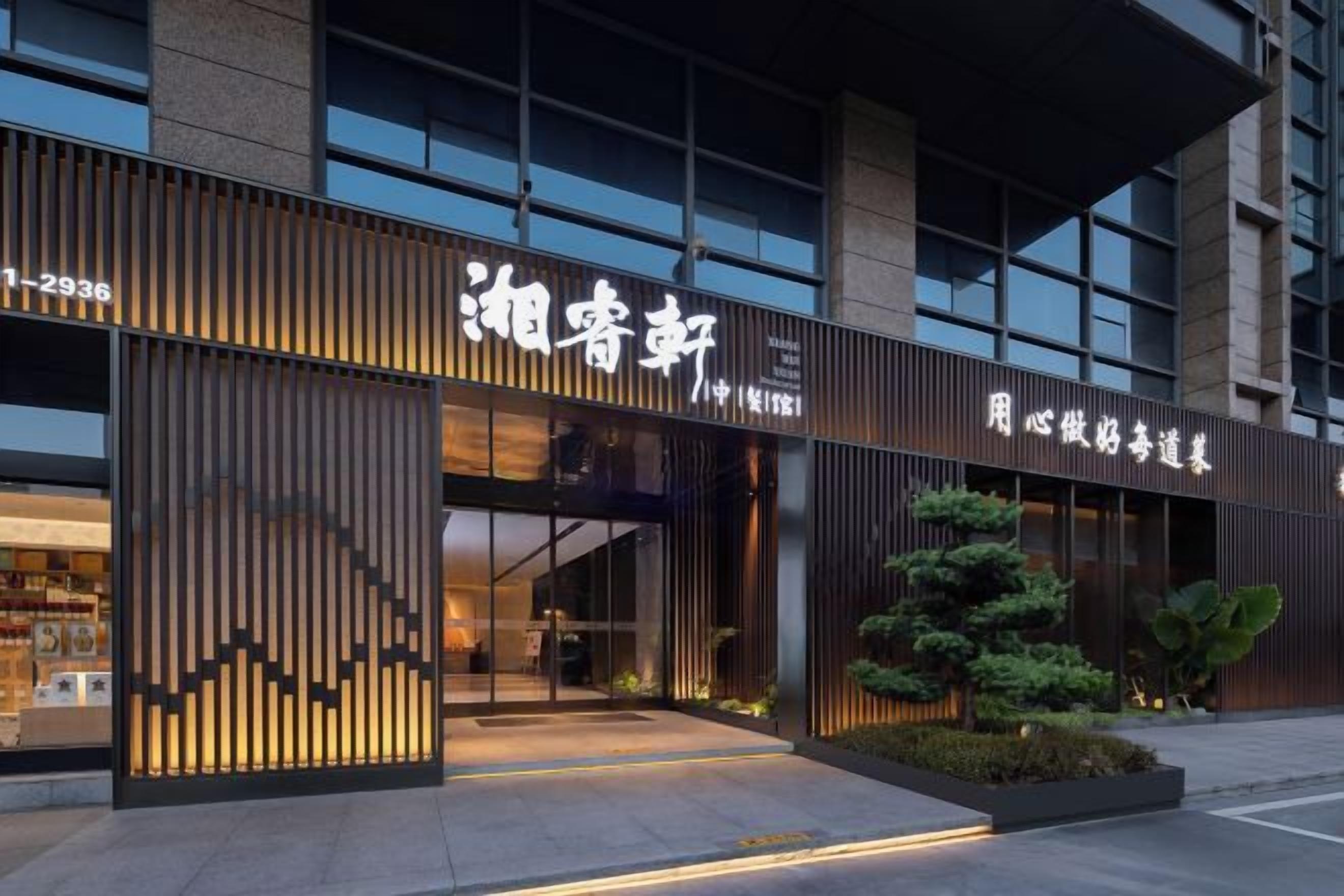 A modern building with a large entrance, signage, and a well-lit facade.