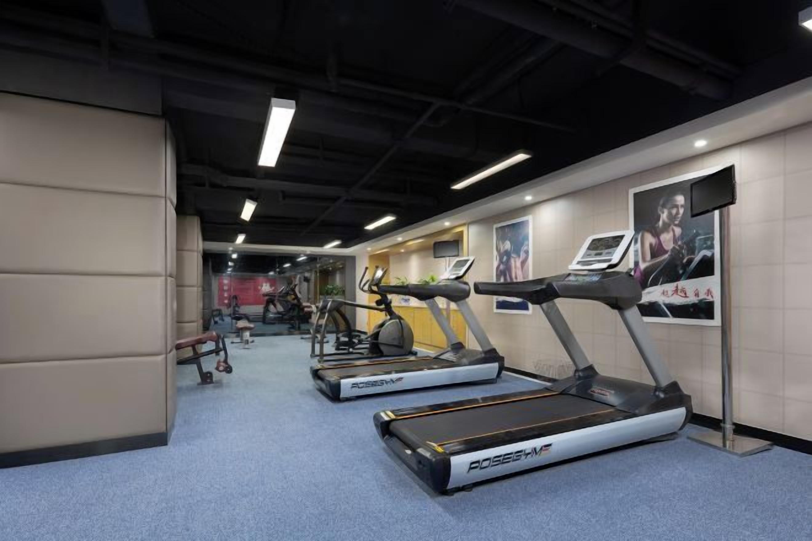 A gym with treadmills, exercise equipment, and a poster on the wall.