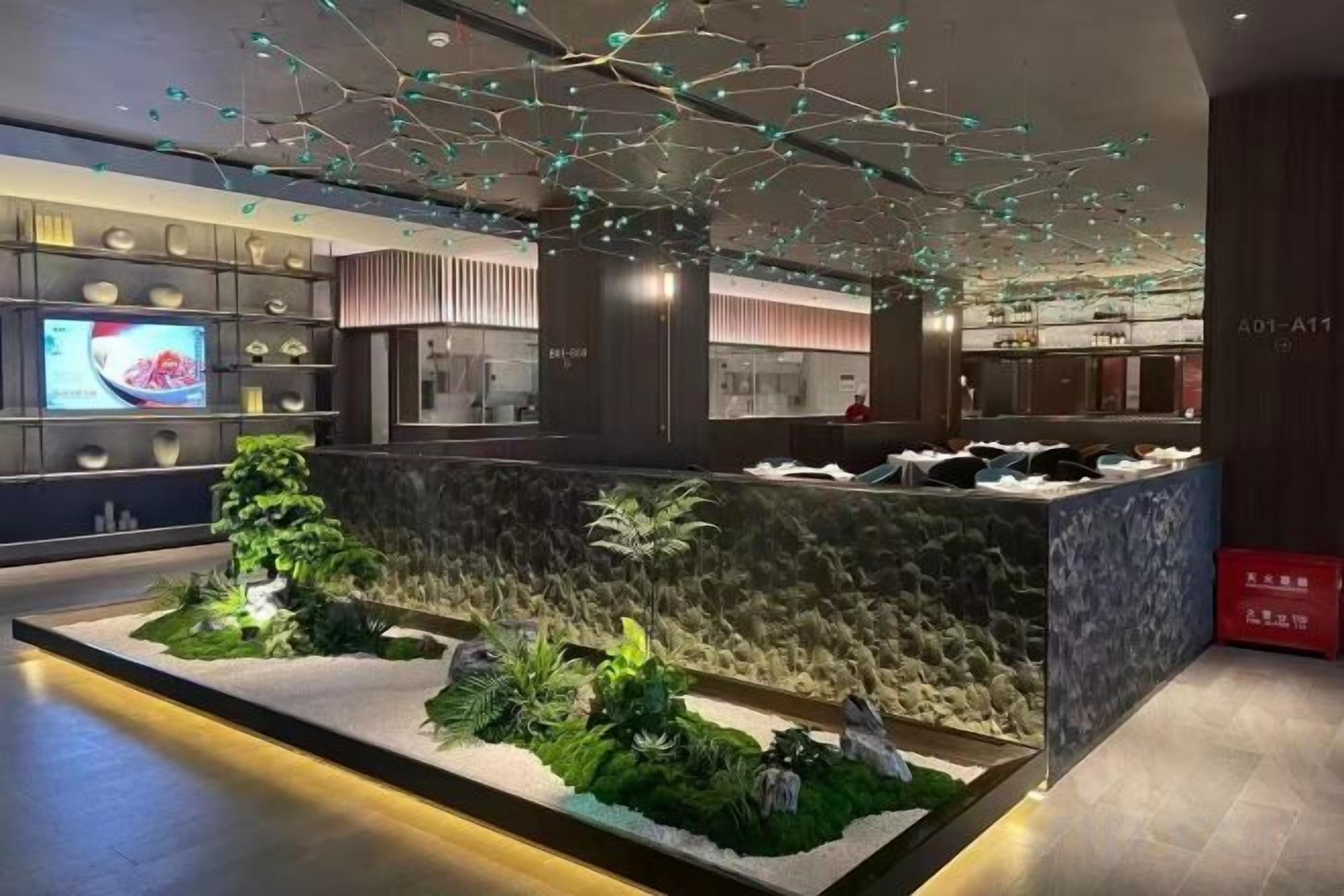 A modern hotel lobby with a reception desk, a television screen, and a decorative ceiling.