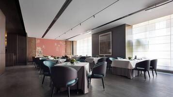 Un comedor moderno con mesas y sillas, ventanas amplias y una paleta de colores neutros.
