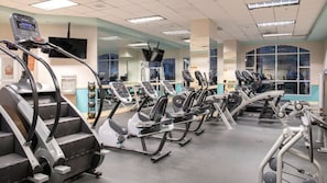 Una palestra con diverse tapis roulant, ellittiche e macchinari per pesi.