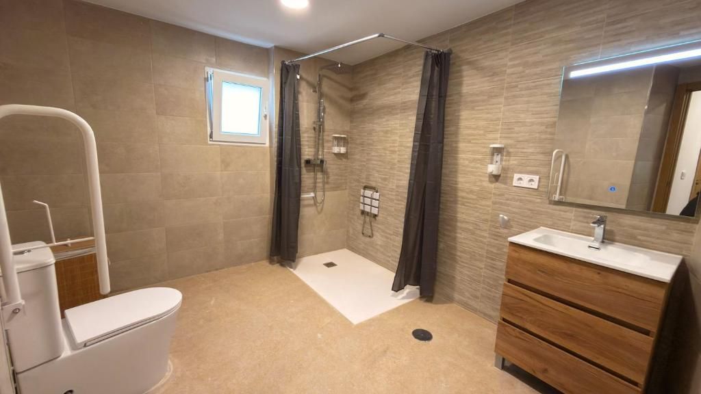 Un baño moderno con inodoro, ducha y tocador.
