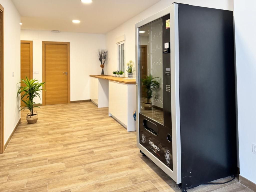 A hallway with wooden flooring, a black refrigerator, and two wooden doors.