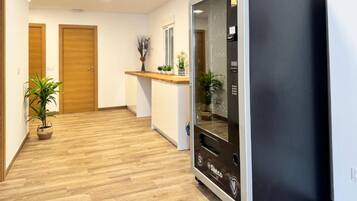 A hallway with wooden flooring, a black refrigerator, and two wooden doors.