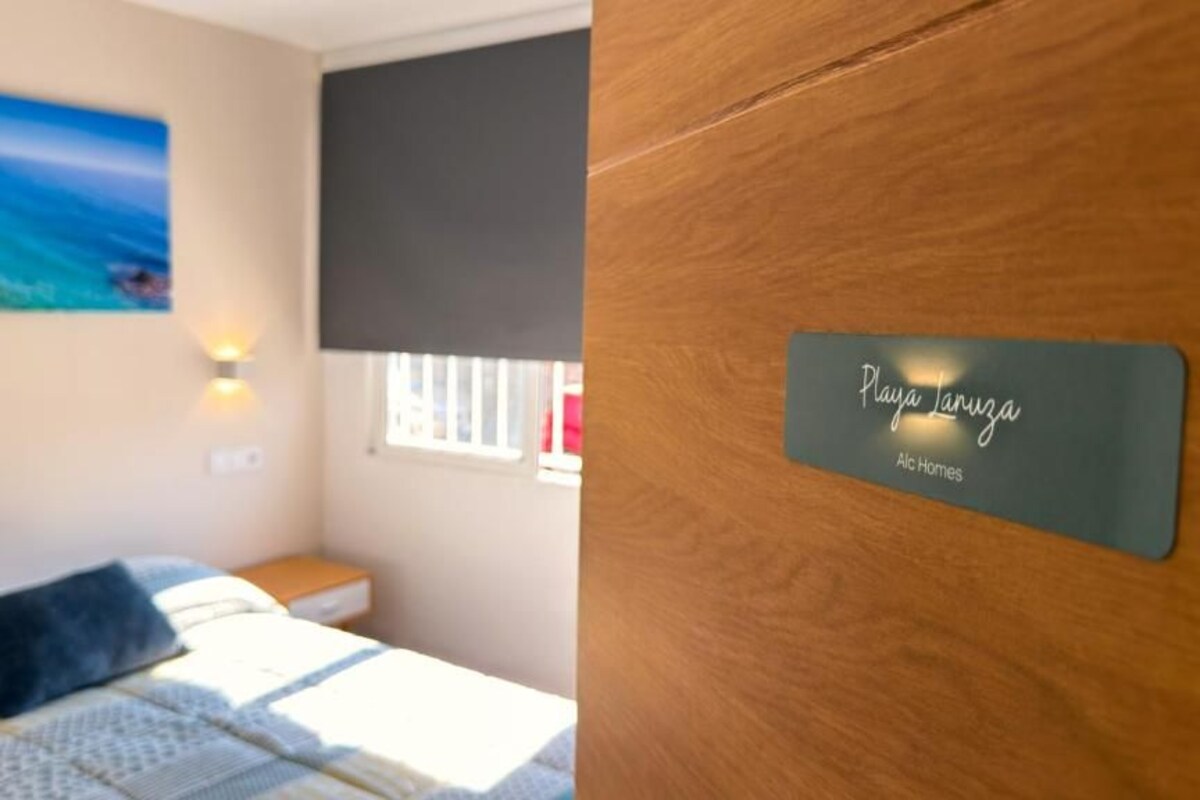 Een slaapkamer met een bed, een strandafbeelding, een raam met uitzicht en een plaquette aan de muur.