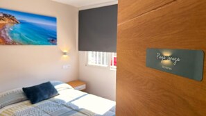 Een slaapkamer met een bed, een strandafbeelding, een raam met uitzicht en een plaquette aan de muur.