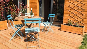 A wooden deck with a table and chairs, surrounded by wooden planters with plants. - Vrbo Property (Bernardvillé)