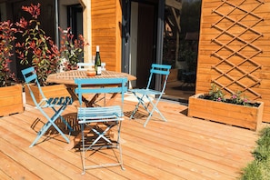 Une terrasse en bois avec une table et des chaises, entourée de jardinières en bois remplies de plantes.