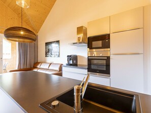 A modern kitchen with a built-in island, stainless steel appliances, and a pendant light. - Apartment With 1 Bedroom (Sankt Georgen am Kreischberg)