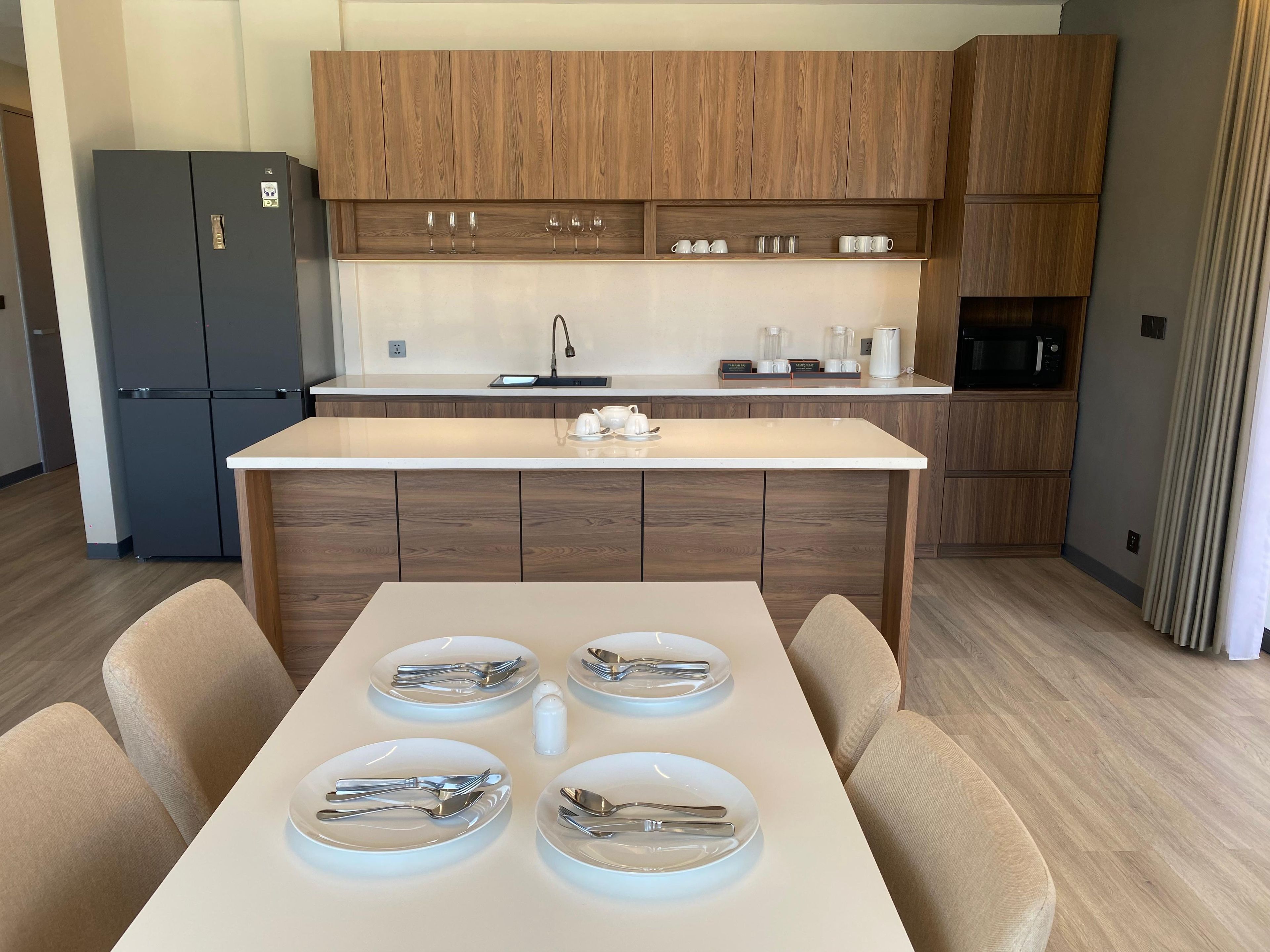 A modern kitchen with wooden cabinets, a built-in microwave, and a dining area with a table set for four.