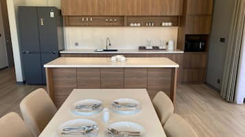 A modern kitchen with wooden cabinets, a built-in microwave, and a dining area with a table set for four.