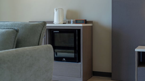 A modern room with a built-in fireplace, a coffee maker, and a sign for Tampah Bay Boutique Resort. - Tampah Bay Boutique Resort (Kuta)