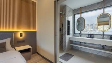 A modern bedroom with a bed, bedside table, and a wall-mounted light.