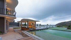 A modern resort with a pool, a bar area, and a view of the ocean. - Tampah Bay Boutique Resort (Kuta)