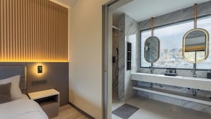 A modern bedroom with a bed, bedside table, and a wall-mounted light. - Tampah Bay Boutique Resort (Kuta)
