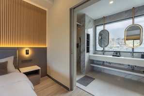 A modern bedroom with a bed, bedside table, and a wall-mounted light. - Tampah Bay Boutique Resort (Kuta)