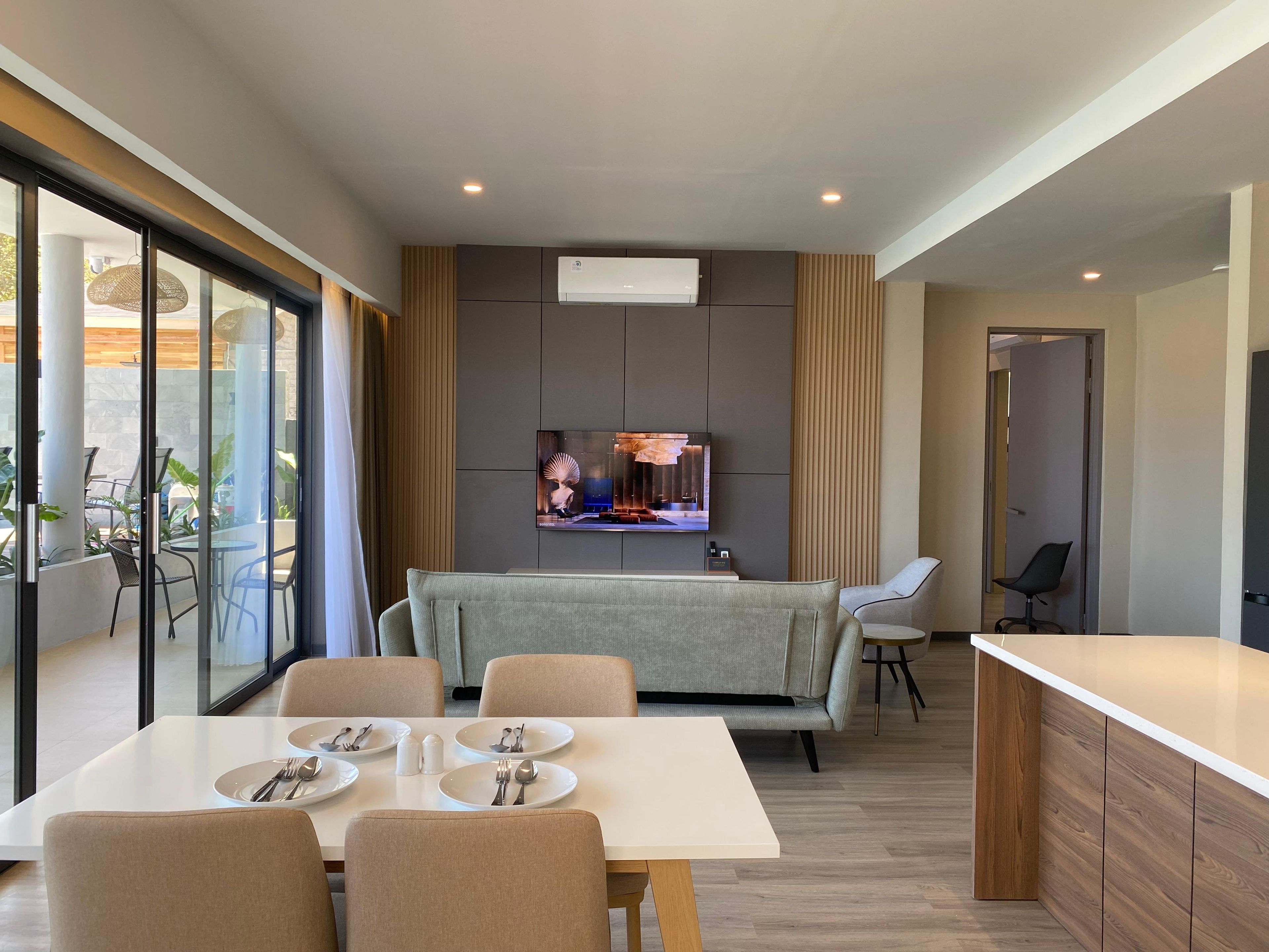 A modern dining area with a TV mounted on the wall, a sofa, and a dining table set for four.