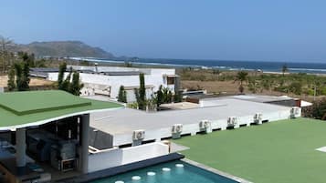 A rooftop pool with a clear view of the ocean and hills in the background.