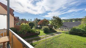 Ein Wohnhaus mit einem Balkon, der einen Garten und die umliegende Landschaft mit freiem Blick bietet.