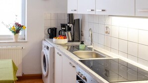 Eine moderne Küche mit weißen Schränken, einer integrierten Waschmaschine, einem Herd und einem Spülbecken.
