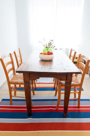 Una mesa de madera con un cuenco de fruta y un jarrón de flores.