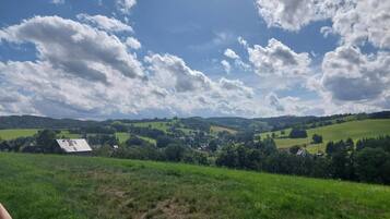 A rural landscape with rolling hills, scattered houses, and a clear sky with clouds.