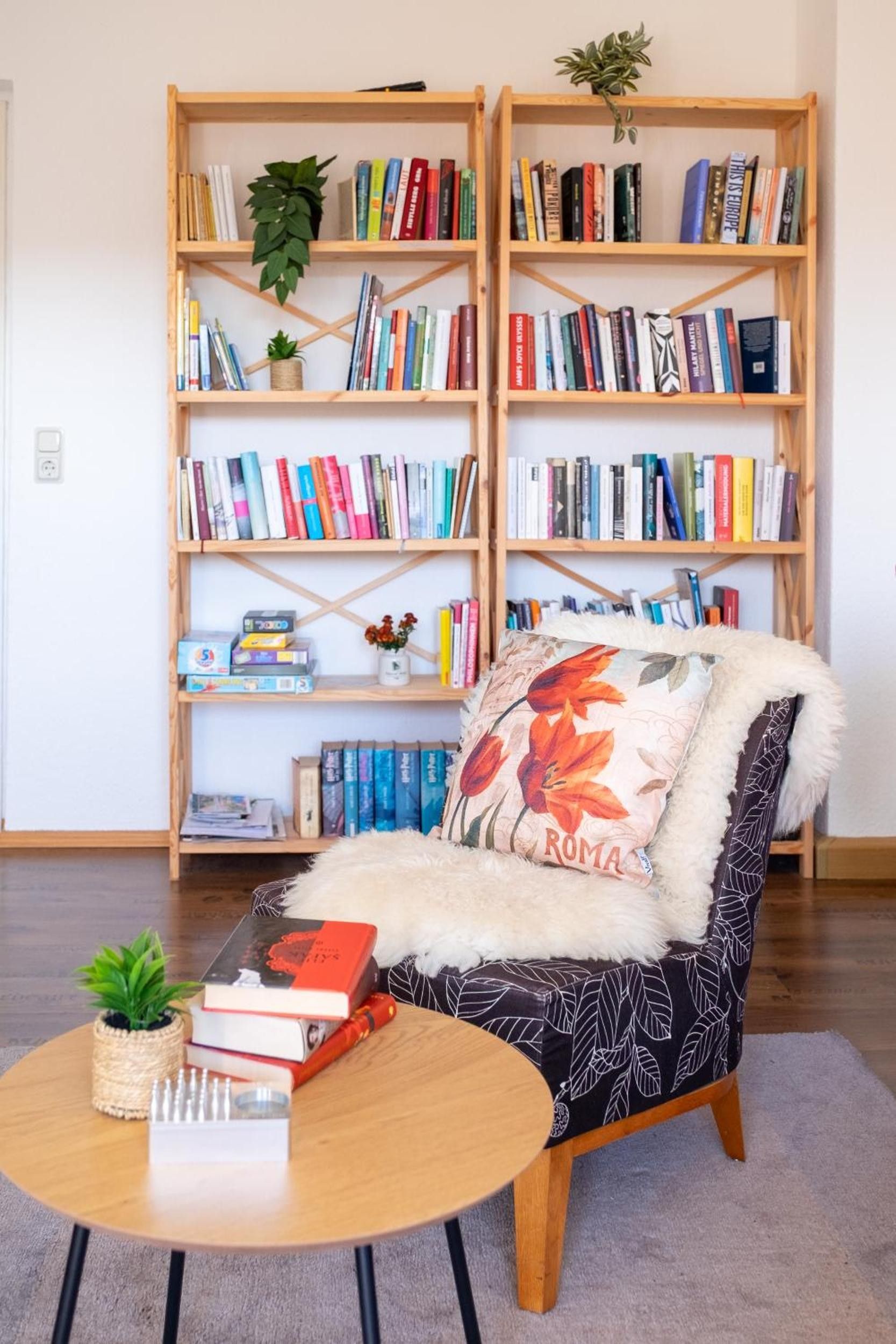 A cozy reading nook with a chair, a small table, and two wooden bookshelves filled with books.